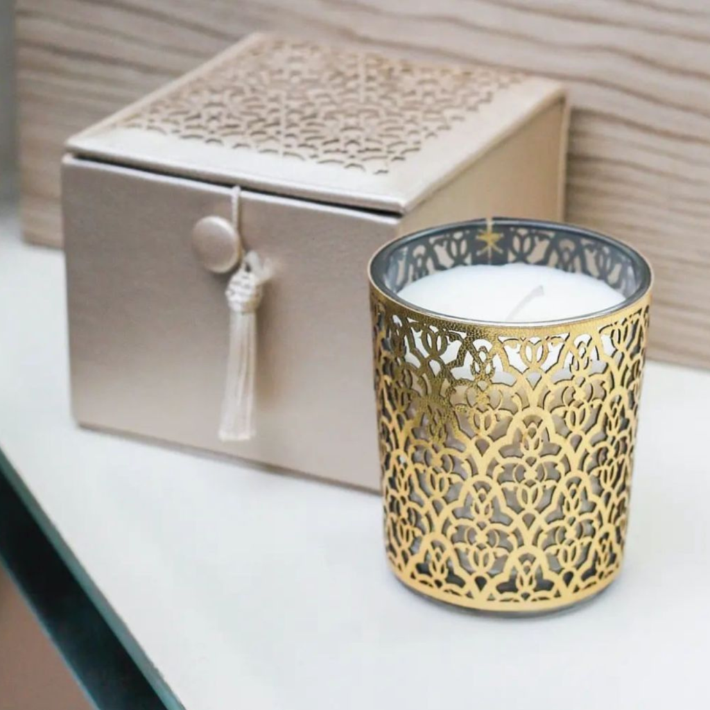 candle with golden perforated casing and beige box behind