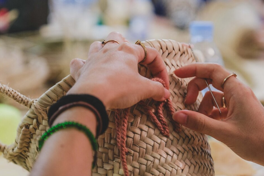 hands with needle embroidering soft pink words on a basket