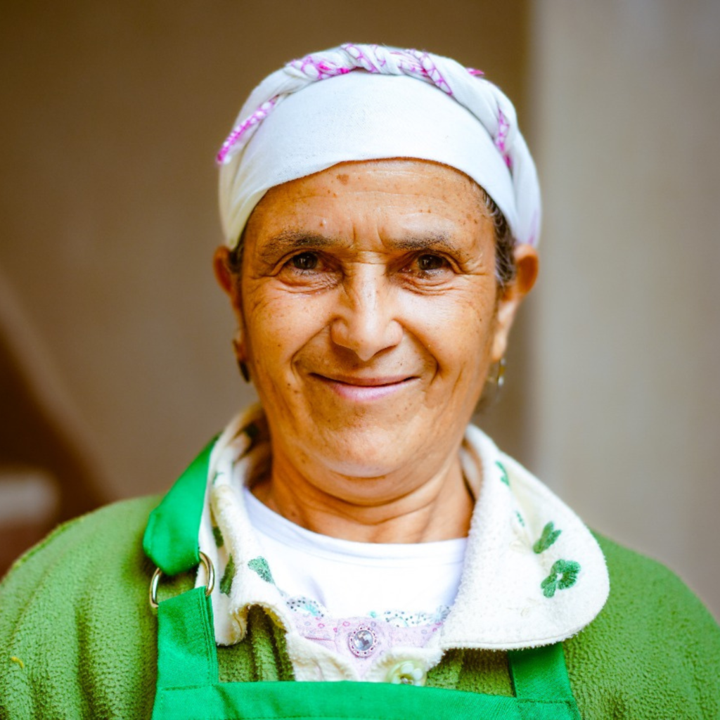 senior lady smiling in green and small chef hat