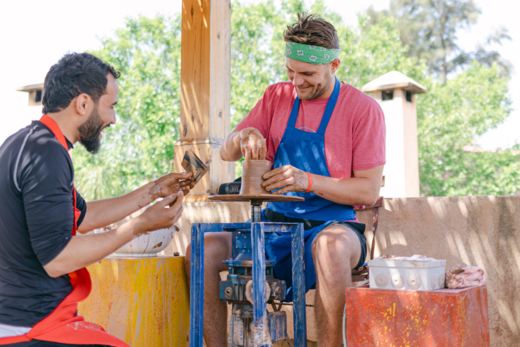 man in blue apron doing pottery