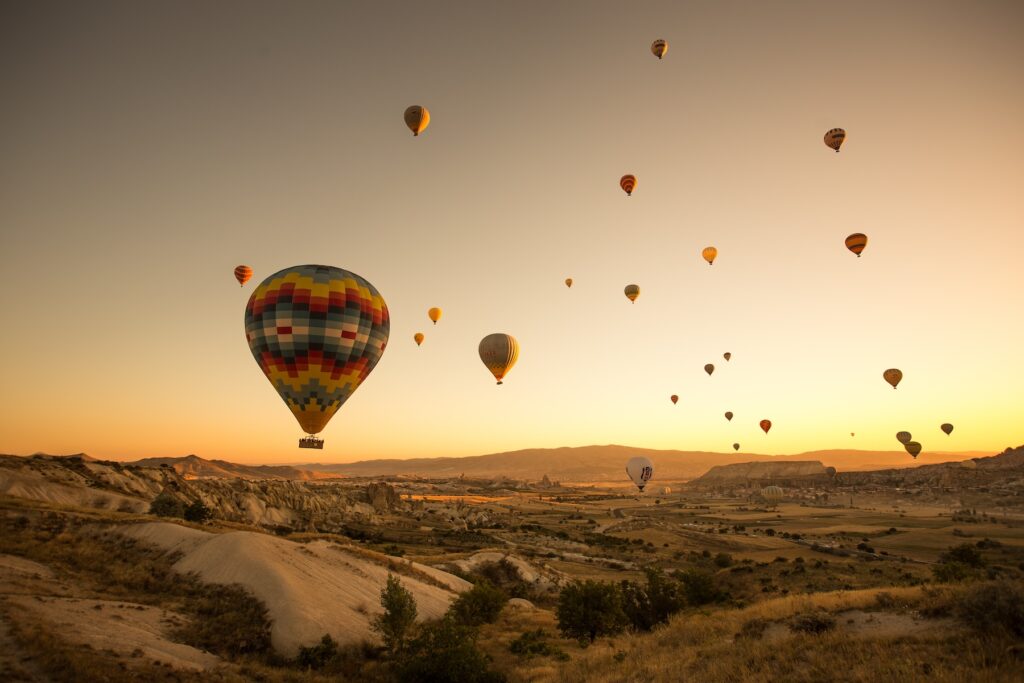 various air balloons in a yellow sunrise-like sky