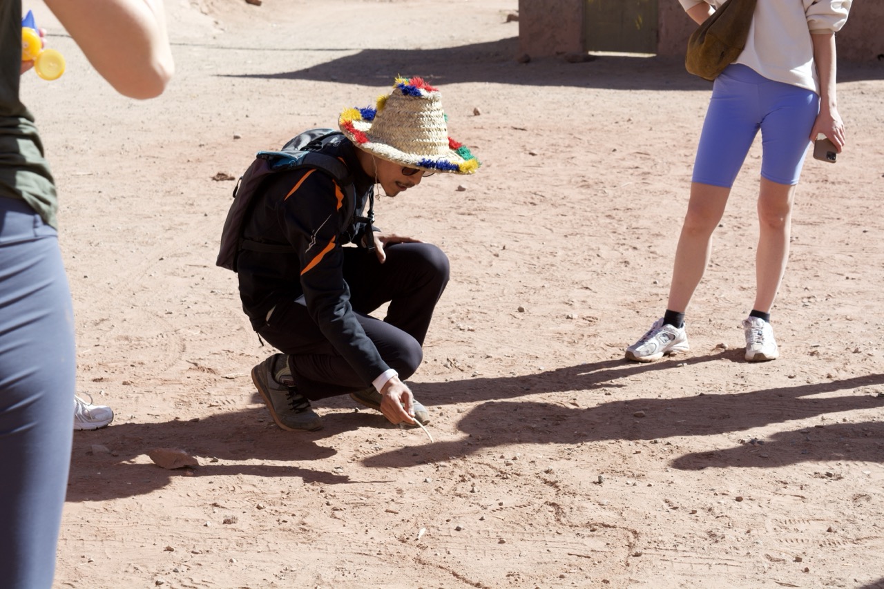 tour guide in ourika drawing something in the sandy ground to explain.